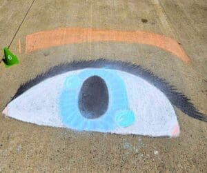 Chalk drawing of a blue eye on pavement.