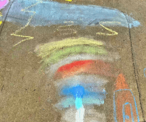 Chalk drawing of a rainbow on sidewalk.