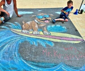 Chalk drawing of dog surfing with boy.